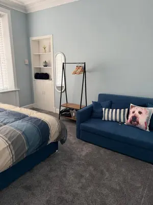 a bedroom with a blue couch and a bed at Woodside Bungalow in Stevenston