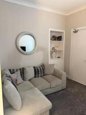 a living room with a couch and a mirror at Woodside Bungalow in Stevenston