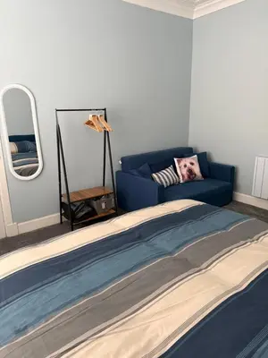 a bedroom with a blue bed and a couch at Woodside Bungalow in Stevenston