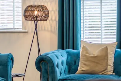 a blue couch with a pillow next to a floor lamp at Modern 2-Bed Apt, Private Parking, Ayr Town Centre in Ayr