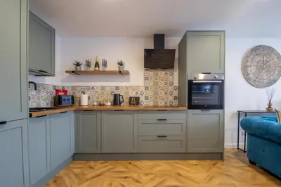 a kitchen with white cabinets and a blue couch at Modern 2-Bed Apt, Private Parking, Ayr Town Centre in Ayr