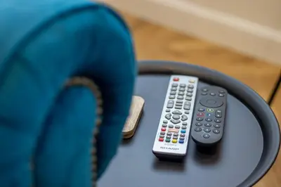 two remote controls sitting on a table next to a blue chair at Modern 2-Bed Apt, Private Parking, Ayr Town Centre in Ayr