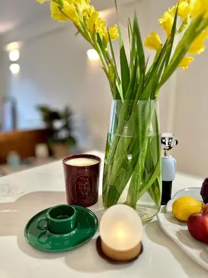 a vase with yellow flowers and a candle on a table at Central London Designer Room with Balcony Elevator in Moffat