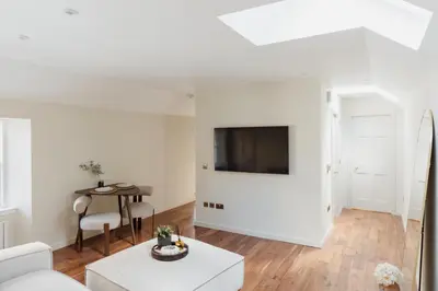 a living room with a couch and a tv on a wall at Charming Central Mews Home with Secure Parking in Edinburgh