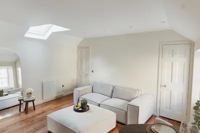 a white living room with a couch and a table at Charming Central Mews Home with Secure Parking in Edinburgh