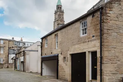 an old brick building with a clock tower in the background at Charming Central Mews Home with Secure Parking in Edinburgh