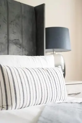a bed with a black and white pillow and a lamp at Arranview Retreat in Airdrie
