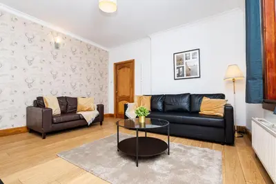 a living room with a couch and a table at 2Bed Upper Cottage-Street Parking-by Holiday Homes in Falkirk