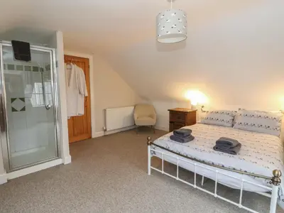 a bedroom with a bed and a walk in shower at The Cottage in Perth