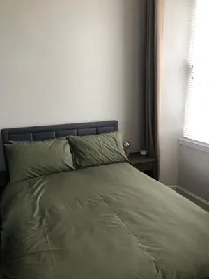 a bed with a green comforter and a window at Charming West End Flat in Edinburgh