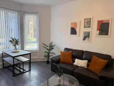 a living room with a black couch and a table at 2BR Flat with Parking Near Glasgow Green and Parks in Glasgow