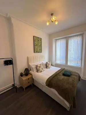 a bedroom with a large bed and a window at 2BR Flat with Parking Near Glasgow Green and Parks in Glasgow