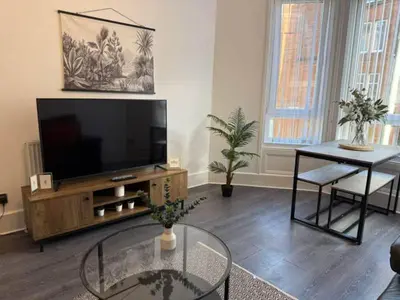 a living room with a flat screen tv and a table at 2BR Flat with Parking Near Glasgow Green and Parks in Glasgow