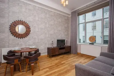 a living room with a table and chairs and a television at Stylish Merchant City Flat Glasgow in Glasgow
