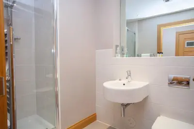 a white bathroom with a sink and a shower at Stylish Merchant City Flat Glasgow in Glasgow