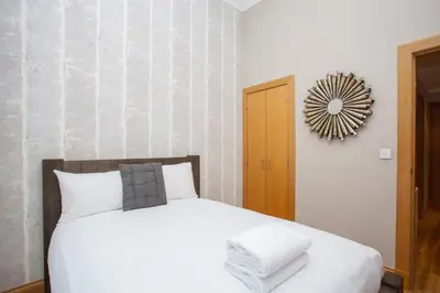 a bedroom with a bed and a clock on the wall at Stylish Merchant City Flat Glasgow in Glasgow