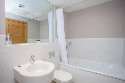 a bathroom with a sink and a toilet and a mirror at Stylish Merchant City Flat Glasgow in Glasgow