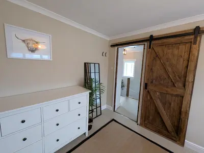 a sliding barn door in a bedroom with a dresser at Newly Refurbished 3 Bed House with 2-Sided Wood Burner and Garden in Edinburgh in Edinburgh