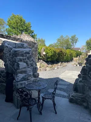 a table and two chairs sitting next to a stone wall at Pink Cottage in Kirkcowan