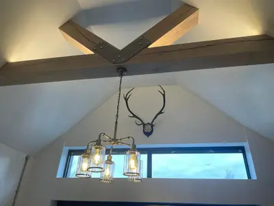 a chandelier hanging from a ceiling with a window at Pink Cottage in Kirkcowan