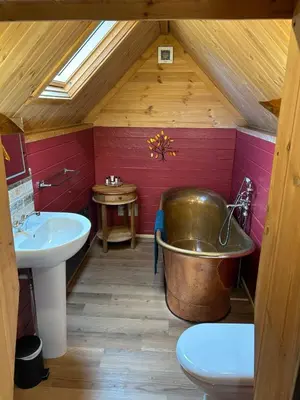 a bathroom with a large copper tub in a attic at Wildcat Lodge in Kilmichael Glassary