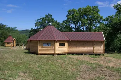 a log cabin with a red roof in a field at Wildcat Lodge in Kilmichael Glassary