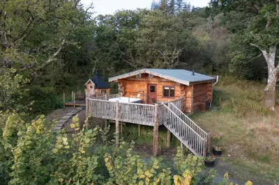a log cabin with a porch and a deck at Pine Marten in Kilmichael Glassary