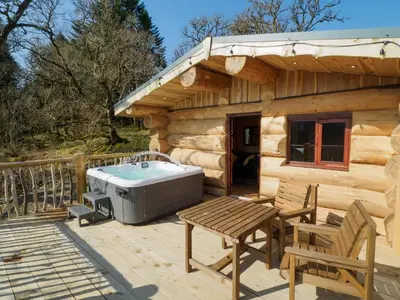 a wooden cabin with a hot tub on a deck at Pine Marten in Kilmichael Glassary