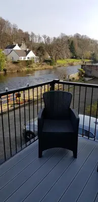 a chair sitting on a deck overlooking a river at Riverside Cottage in Minnigaff