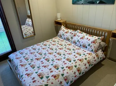a bedroom with a bed with a comforter and a mirror at Skye Lodge in Tighnabruaich