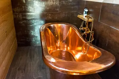 a copper tub in a bathroom with a wall at Woodcock Lodge in Kilmichael Glassary