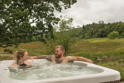 a man and a woman in a hot tub at Woodcock Lodge in Kilmichael Glassary