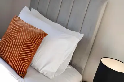 a stack of white pillows on a bed with a brown pillow at Vacant Nests Dunfermline WiFi Priv-Parking in Fife