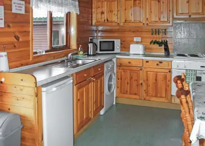 a kitchen with a sink and a washing machine at Hideaway Lodges in Boʼness