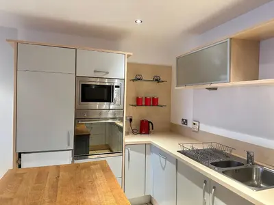 a kitchen with white cabinets and a sink and a microwave at Pier House in Edinburgh
