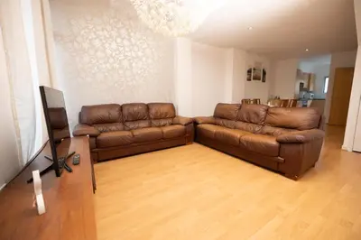 a living room with two leather couches and a television at Muirhouse 2BR Apartment with Free Parking in Glasgow