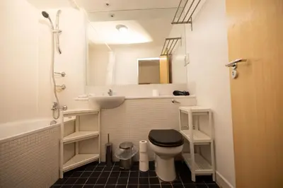 a bathroom with a toilet and a sink and a mirror at Muirhouse 2BR Apartment with Free Parking in Glasgow
