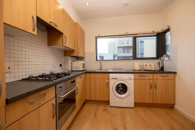 a kitchen with a washing machine and a window at Muirhouse 2BR Apartment with Free Parking in Glasgow