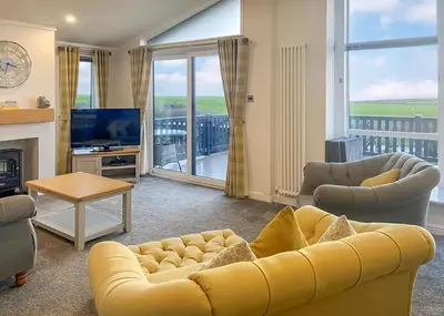 a living room with a yellow couch and a television at Whitecairn Holiday Park in Glenluce