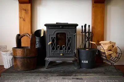 a black stove sitting next to two trash cans at Stunning 2 Bed Riverside Cottage near Oban in Oban