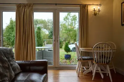 a living room with a couch and a table and a sliding glass door at Stunning 2 Bed Riverside Cottage near Oban in Oban