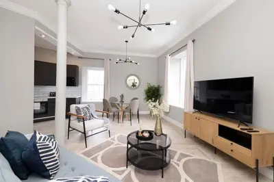 a living room with a large television and a dining room at 1 Bed in the heart of Grassmarket with Castle Views in Edinburgh