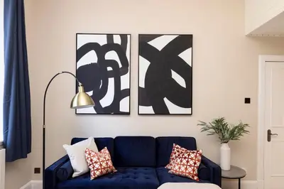 a blue couch in a living room with two pictures at 1 bed in heart of Old Town with Castle Views in Edinburgh