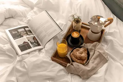 a tray with a book and a plate of bread and orange juice at 1 bed in heart of Old Town with Castle Views in Edinburgh