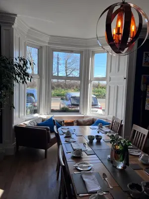 a living room with a table and a large window at Ravenswood Guest House in Stirling