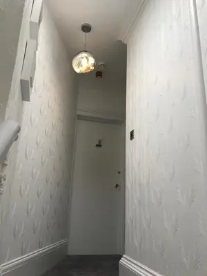 a hallway with a door and a light on a wall at Ravenswood Guest House in Stirling