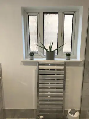 a bathroom with three windows with potted plants on a dresser at Ravenswood Guest House in Stirling