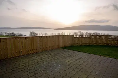 a backyard with a fence and a view of the water at Sunset View in Innellan