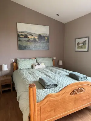 a bedroom with a wooden bed with two pillows on it at Drovers Lodge, farm retreat in rural Lanarkshire, family and pet friendly, onsite craft distillery, perfect location for exploring central Scotland in Forth