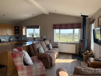 a large living room with a couch and a stove at Drovers Lodge, farm retreat in rural Lanarkshire, family and pet friendly, onsite craft distillery, perfect location for exploring central Scotland in Forth